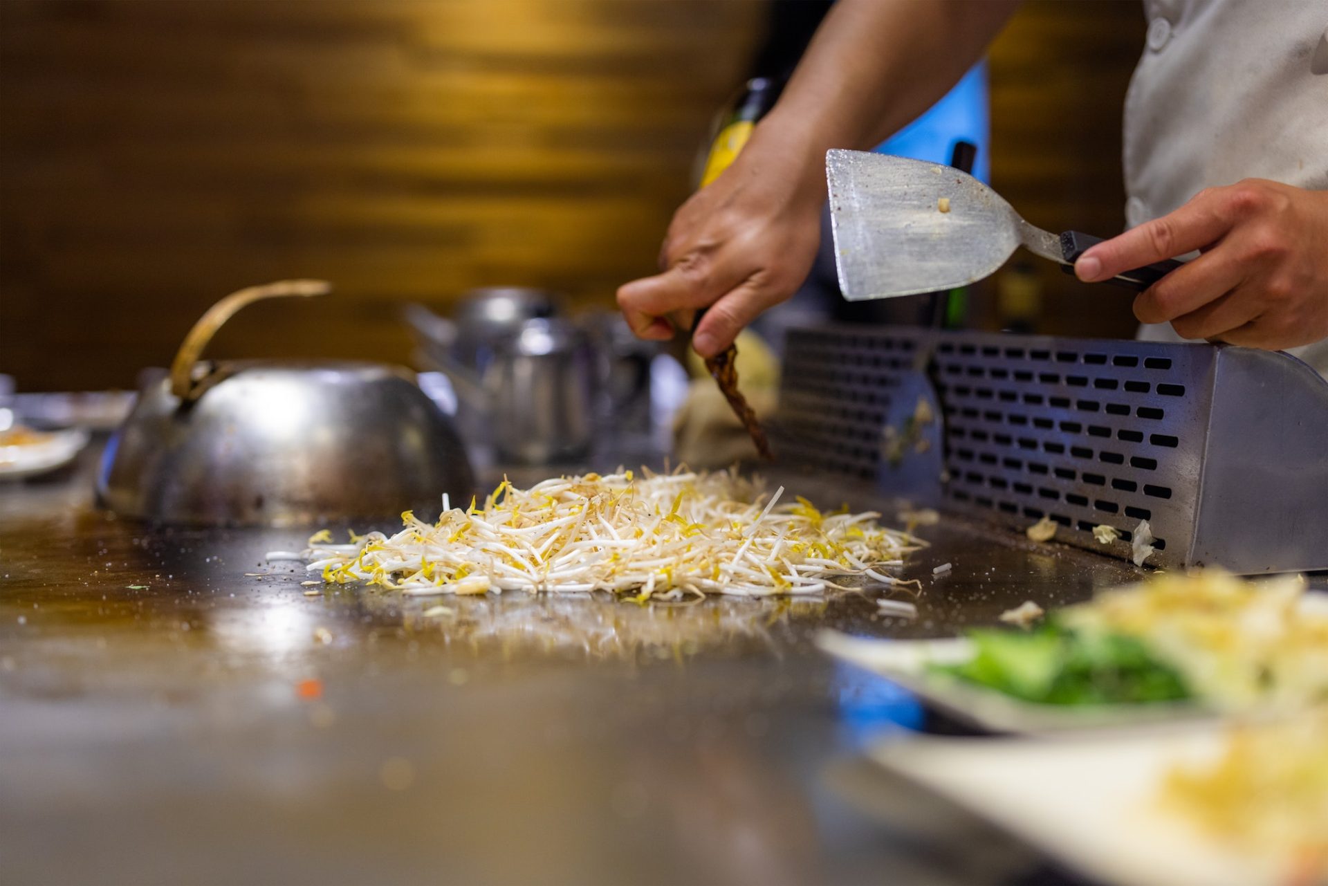 Teppanyaki chef preparing food on hot metal plate